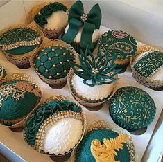 decorated cupcakes with green and gold decorations in a box on the floor next to each other