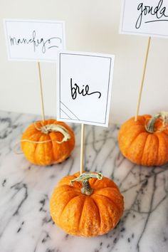 three small pumpkins sitting on top of a marble table with place cards in them