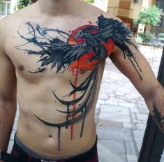 a man with a bird tattoo on his chest is standing in front of a building