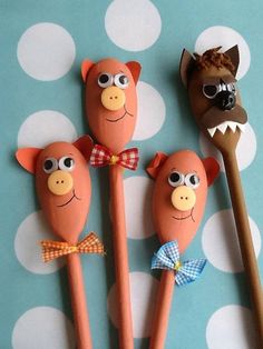 three wooden spoons with pigs on them sitting next to a fake toothbrush holder