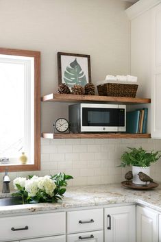 a kitchen with white cabinets and open shelving above the sink, has flowers on the counter