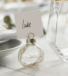 a place card holder is placed on top of a glass ornament at a table