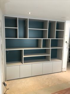 an empty room with blue shelves and white cabinets