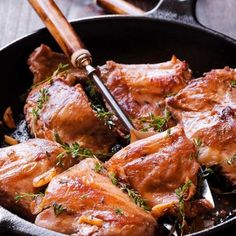 a skillet filled with cooked meat and garnished with herbs