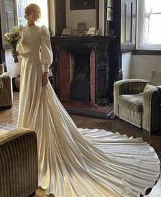 a woman in a wedding dress standing next to a fireplace