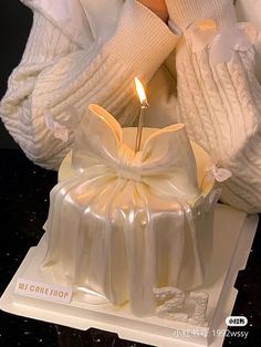 a cake with a candle in the middle on top of a table next to a white sweater