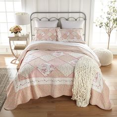 a bed with pink and white bedspread in a bedroom next to a window