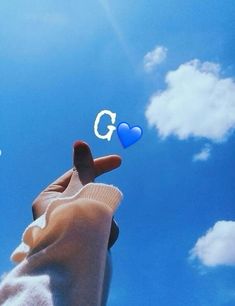 someone holding out their hand with the letter g on it and blue sky in the background