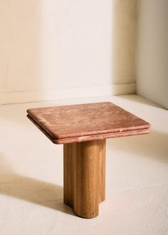 a small wooden table sitting on top of a white carpeted floor next to a window