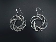 the earrings are made from metal and have spiral designs on them, as well as circular hoop