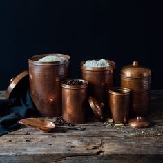 a wooden table topped with copper canisters filled with rice