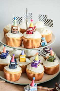 cupcakes decorated with cars and race flags are on a cake platter, ready to be eaten