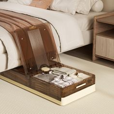 an open suitcase sitting on the floor in front of a bed with white sheets and pillows