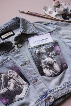 an altered jean jacket with pictures of people on it and paintbrushes next to it