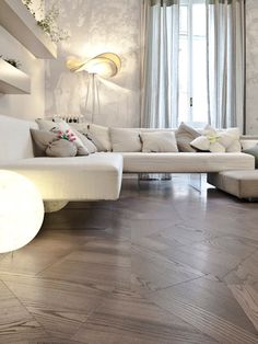 a living room filled with white furniture next to a large window and wooden flooring