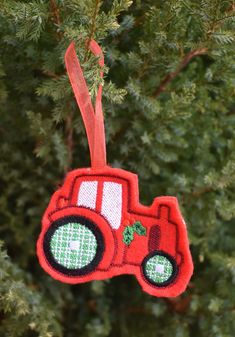 a red tractor ornament hanging from a tree