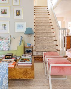 a living room filled with lots of furniture and pictures on the wall above it's stairs