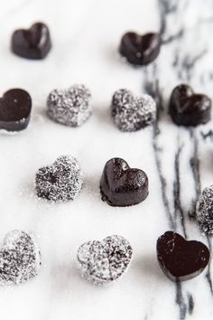 chocolate hearts are sitting in the snow on top of some white and black marbles