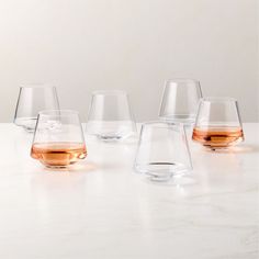 four glasses are lined up on a table with one filled with liquid and the other empty