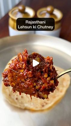 a spoon full of food sitting on top of a metal pan with sauce in it