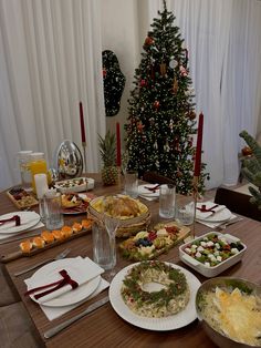 a christmas tree is in the background with many plates and bowls on it