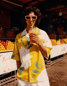 a woman wearing sunglasses and holding a drink