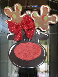 a wooden reindeer head with a red bow hanging from it's side on a wall