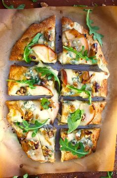 a pizza cut into eight slices on top of a piece of parchment paper with green toppings