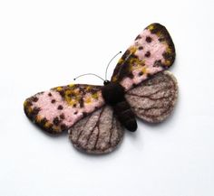 a pink and brown butterfly sitting on top of a white surface