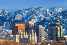 a city with mountains in the background and snow on the top of the mountain tops