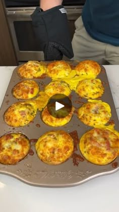 a pan filled with muffins sitting on top of a counter next to a person