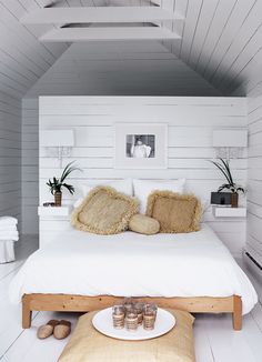 a bedroom with white walls and flooring is decorated in natural materials, including pillows