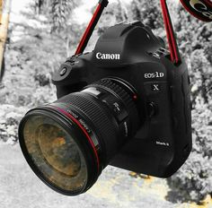 a canon camera hanging from a tree with its lens attached to it's body