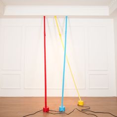 two plastic poles are connected to wires in an empty room with white walls and wood flooring