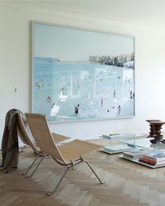 a living room filled with furniture and a large painting on the wall above it's glass coffee table