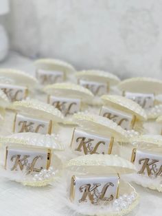 wedding favors with initials on them sitting on a white table cloth covered tablecloth in front of a wall