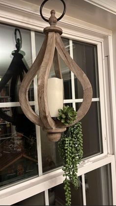 a candle hanging from the side of a window next to a potted plant in front of it