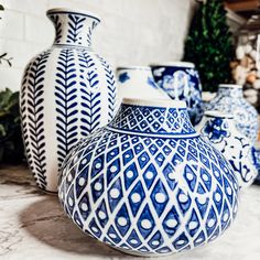 several blue and white vases sitting on top of a marble counter next to potted plants