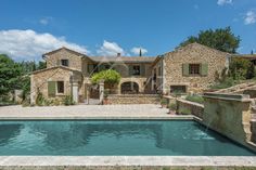 an outdoor swimming pool in front of a stone house