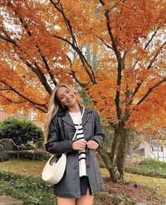 a woman standing in front of a tree with her hand on her hip while wearing knee high boots