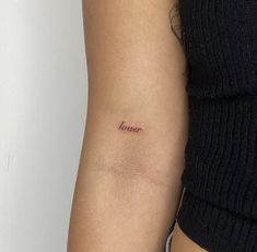 a woman's arm with a small tattoo on it that says love in cursive writing