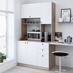 a kitchen with white cupboards and counter tops next to a window in an apartment