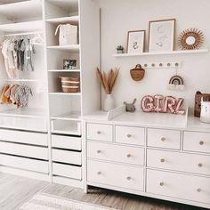 a room with white furniture and shelves filled with baby items, such as toys and pictures