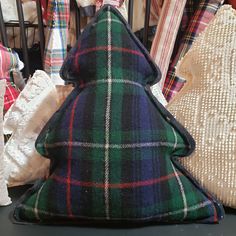 a christmas tree pillow sitting on top of a table next to other pillows and blankets