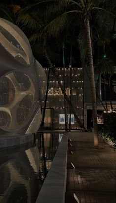 a large white object sitting on top of a pool next to a palm tree at night