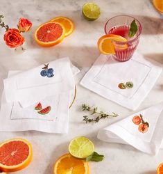 oranges, watermelon slices and other fruit are scattered around the napkins