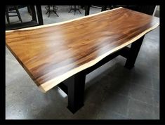 a wooden table with black metal legs in a room filled with tables and stools