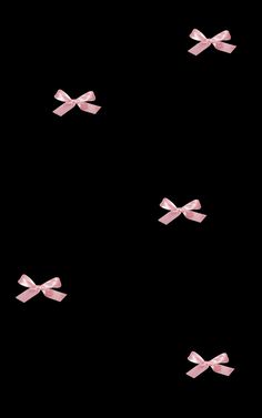 pink bows flying in the air on a black background