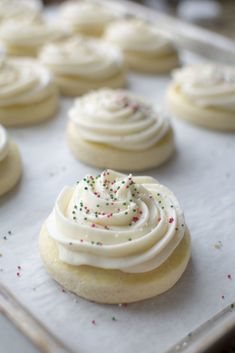 there are many cookies with white frosting and sprinkles on the tray