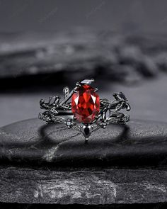 a red stone ring sitting on top of a rock